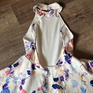 Open back floral, white dress. High neck, with a flare.